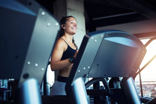 Smiling woman exercising and training in the gym on treadmill running machine. Healthy lifestyle and positive people.