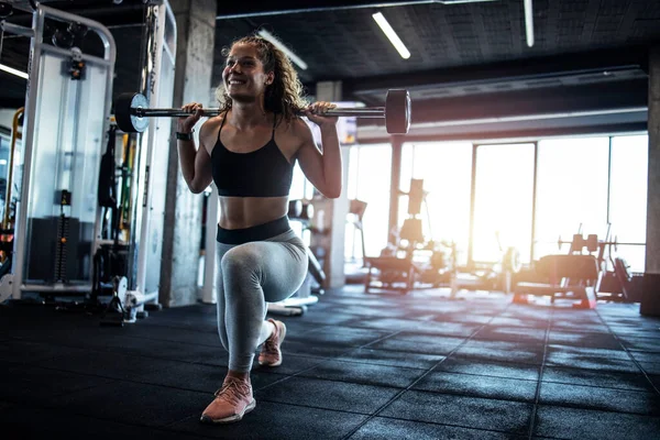 Female exercising with weights in the gym. Bodybuilding and training in fitness center.