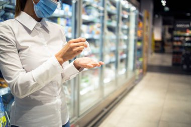 Süpermarketten alışveriş yaparken Corona virüsüne karşı ellerini sterilize et. Sağlıklı kalmak için dezenfekte edilen ellere yakından bakın. Covid-19 koruma tedbirleri.