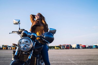 Deri ceketli bayan motosikletçi retro motorsiklette oturuyor ve eğleniyor. Özgürlük ve mutluluk.