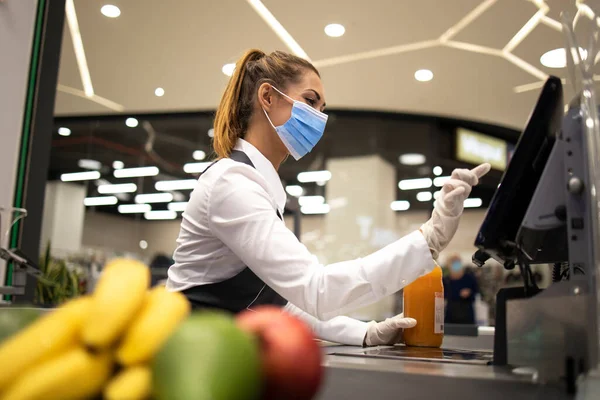 İnsanlar Corona virüsü yüzünden işyerlerinde tehlikede. Süpermarkette çalışan ve COVID-19 veya Corona virüsüne karşı savaşan koruyucu maske ve eldivenli kasiyer..