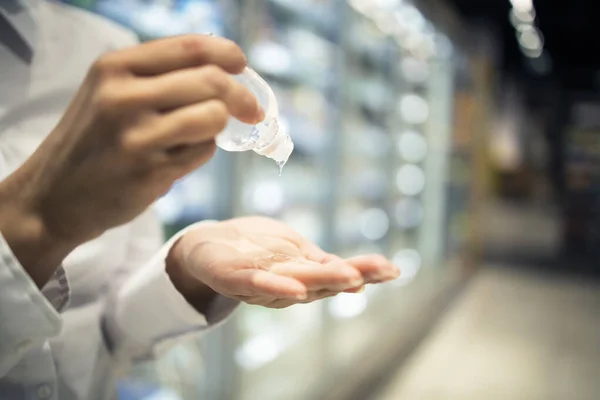 Hands sanitizing against corona virus while shopping in supermarket. Close up view of hands rubbing disinfection to stay healthy. Covid-19 protection measures.