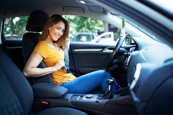 Car interior view of female driver putting seat belt on. Buckle up and drive safe.