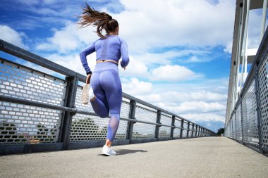 Güzel güneşli bir günde koşan bir bayan koşucu. Eğitim ve sağlıklı yaşam tarzı.