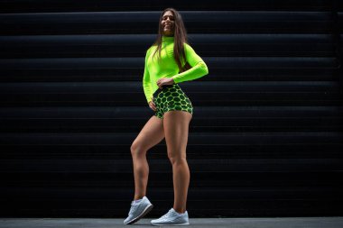 Uzun saçlı, güçlü bacaklı, siyah arka planda poz veren kaslı seksi sporcu kadın sporcunun portresi. Fitness ve vücut geliştirme.