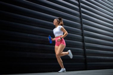 Siyah arka planda koşan ve koşan bayan sporcu.