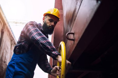 Endüstriyel işçiler direksiyonu çeviriyor ve tren vagonunun vanasını kapatıyorlar. Tren araç bakımı.