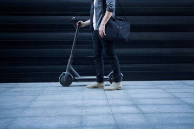 Elektrikli scooterının yanında duran omuz çantalı, tanınmayacak kadar yakışıklı birini vurdu. En iyi gidiş-dönüş aracı.