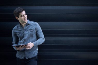 Tablet bilgisayarını tutan ve yan bakan yakışıklı beyaz adamın portresi. Boşluğu kopyala.