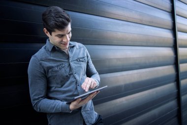 Tablet bilgisayarında yazı yazan yakışıklı beyaz bir adam. İş adamı e- postaları kontrol ediyor.