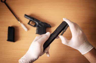 Atış poligonunda kullandıktan sonra ateşli silah temizliği ve bakım. Tabanca parçalara ayrıldı ve barut kalıntılarını temizlemek için fırça kullanıldı.