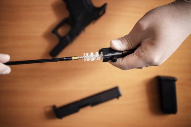Tabanca namlusunu fırçayla temizliyorum. Atış poligonunda kullandıktan sonra ateşli silah temizliği ve bakım. Tabanca parçalara ayrıldı ve barut kalıntılarını temizlemek için fırça kullanıldı.