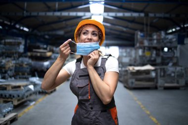 Fabrika binasında çalışan sanayi işçisi kendini son derece bulaşıcı korona virüsünden ya da COVID-19 'dan korumak için yüzüne hijyenik maske takıyor. Küresel virüs salgınında çalışan insanlar.