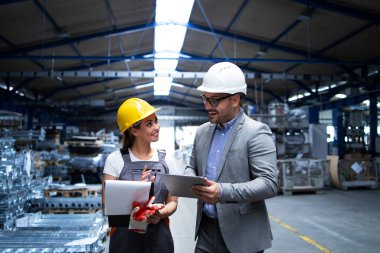 Müdür ve işçi üretim sonuçları ve fabrika endüstriyel salonundaki yeni strateji hakkında tartışıyorlar. Endüstri ve iş.