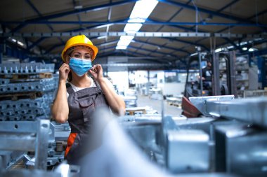 Üniformalı kadın işçi portresi ve endüstriyel üretim fabrikasında yüz maskesi takan kadın. COVID-19 salgını sırasında çalışanlar.