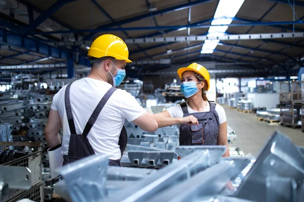 由于全球日冕病毒的流行和感染的危险 工人们以肘部碰撞互相致意 站在工厂里戴防护面具的员工 — 图库照片