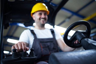 Depo çalışanı forklift makinesi kullanıyor. Kontrol çubuğuna odaklan.