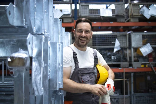 Portrait of factory worker standing in factory production hall. People working in industry.