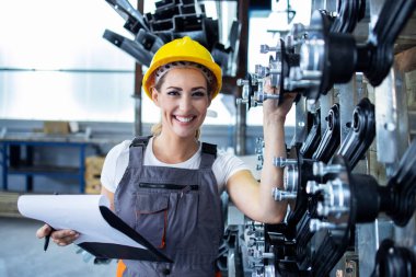 Çalışan üniformalı ve fabrika üretim hattında duran kadın endüstriyel işçinin portresi.