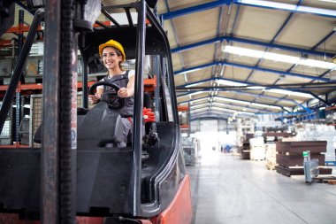 Fabrika binasında forklift kullanan profesyonel kadın endüstriyel sürücü..