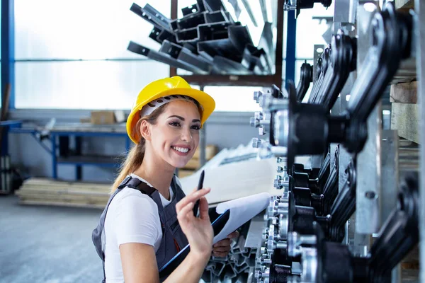 工場で制服やハード帽子の生産をチェック作業中の女性産業従業員 — ストック写真