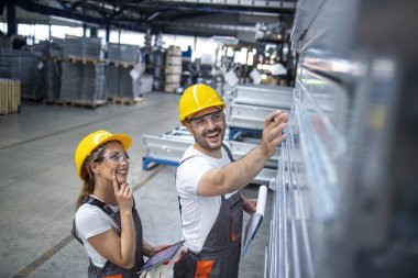 Fabrikadaki metal ürünlerinin kalitesini kontrol eden endüstriyel işçiler.