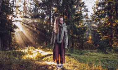 Genç kadın sonbaharda dreadlocks ile düşmek orman sabah ışığında