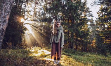 Genç kadın sonbaharda dreadlocks ile düşmek orman sabah ışığında