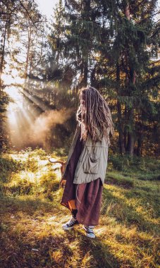 Genç kadın sonbaharda dreadlocks ile düşmek orman sabah ışığında