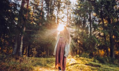 Genç kadın sonbaharda dreadlocks ile düşmek orman sabah ışığında