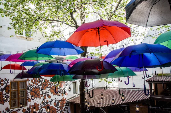 umbrellas hanging above the head with lamps, in the open air