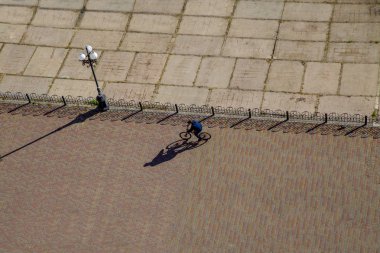 Bisikletçi rides kiremit road, güneşli bir gün, uzun gölgeler, fener, üstten görünüm, arka plan