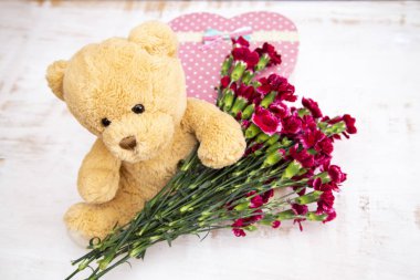 Şirin oyuncak - ayı ile Bordo karanfil ve bir hediye, açık renkli bir kalp şeklinde bir kutu 