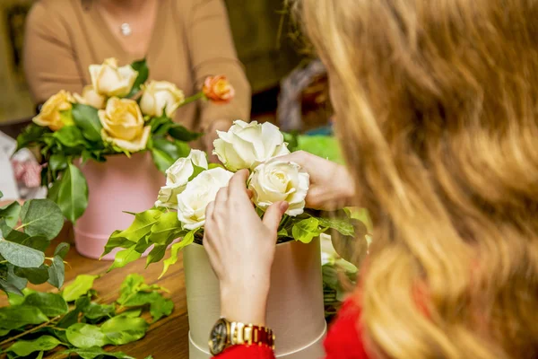 a girl makes a bouquet of white roses in a white box, a master class or work in a flower shop