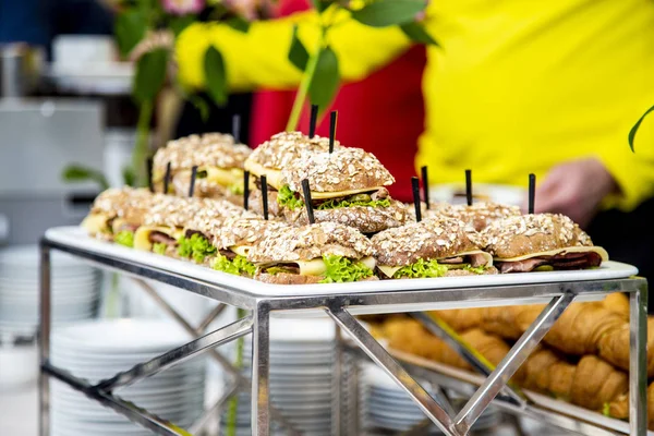 Close up of mini hamburgers at catering event on some festive event, party or wedding reception/ mini burgers with grilled mackerel, tartar sauce, fresh cucumber and ice salad