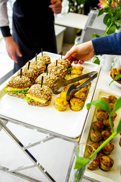 mini tarts with champignons and mini burgers with fried mackerel, tartar sauce, fresh cucumber and ice salad at catering event on some festive event, party or wedding reception