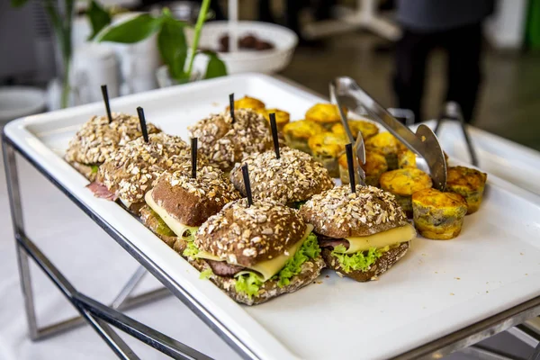 mini tarts with champignons and mini burgers with fried mackerel, tartar sauce, fresh cucumber and ice salad at catering event on some festive event, party or wedding reception