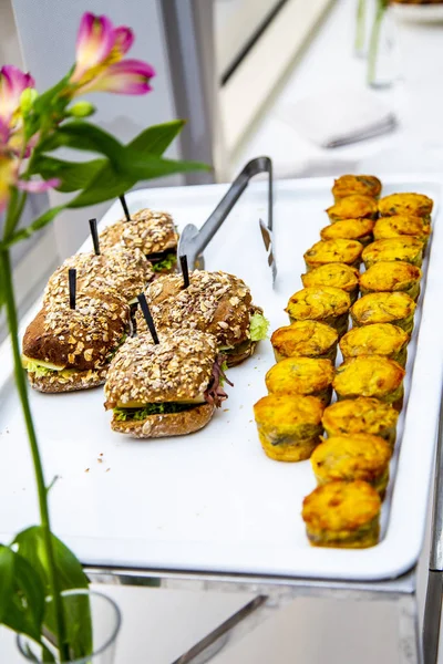 mini tarts with champignons and mini burgers with fried mackerel, tartar sauce, fresh cucumber and ice salad at catering event on some festive event, party or wedding reception