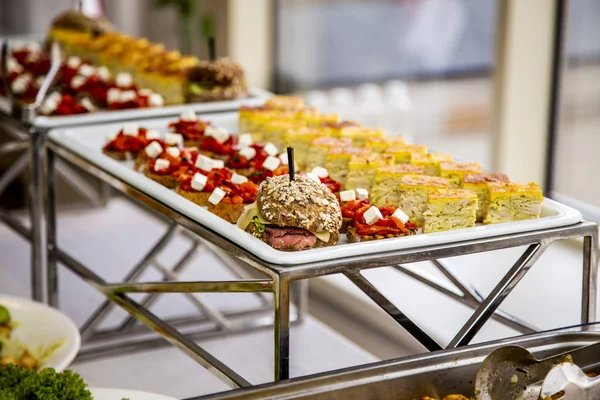 bruschetta on grilled bread with soft cheese and vegetable ratatouille, quiche loren and mini burger with veal pastry, cheese, mustard sauce and cucumber at catering event on some festive event, party or wedding reception