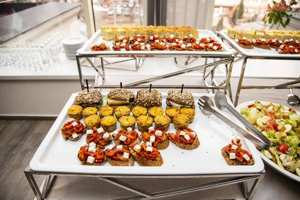 bruschetta on grilled bread with cottage cheese and vegetables ratatouille, quiche loren with chicken and cheese mini burger with veal pastry, cheese, mustard sauce and cucumber,  at catering event on some festive event, party or wedding reception