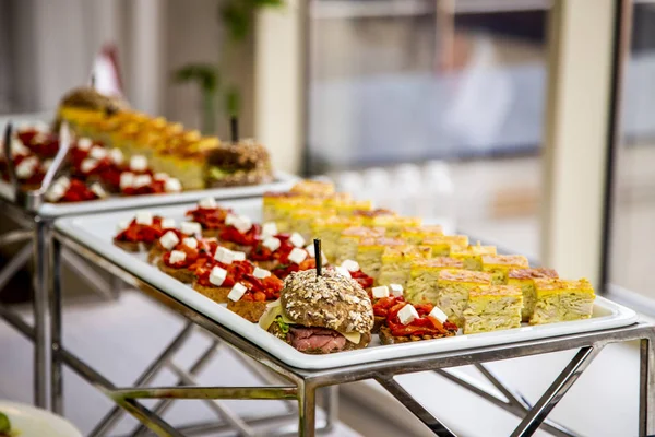 bruschetta on grilled bread with soft cheese and vegetable ratatouille, quiche loren and mini burger with veal pastry, cheese, mustard sauce and cucumber at catering event on some festive event, party or wedding reception