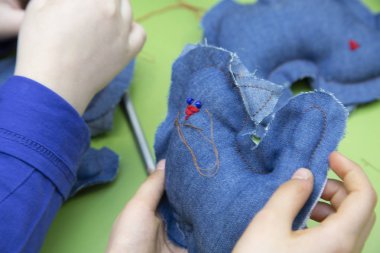 Bir ders ya da bir dikiş Atölyesi - çocuk elleri koyu mavi kumaş oyuncak dikmek