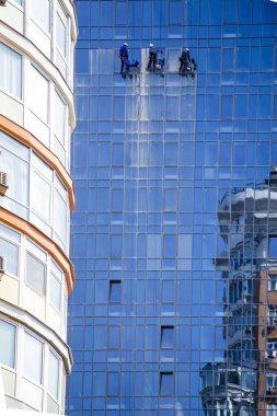 3 erkek yüksek, kentsel modern inşaat ve tehlikeli işgal yansıtılmış pencereleri yıkayın