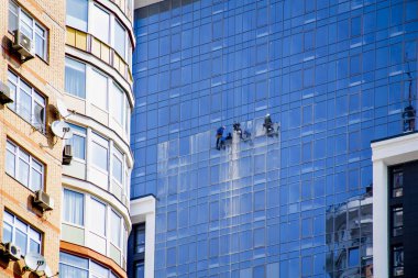 3 erkek yüksek, kentsel modern inşaat ve tehlikeli işgal yansıtılmış pencereleri yıkayın