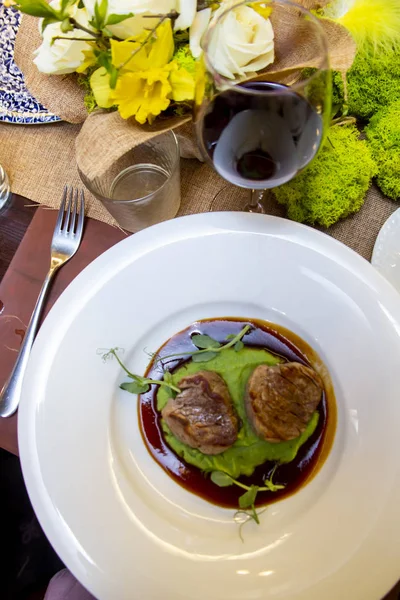 Medalioane de carne de vită din marmură cu sos demi-glace în farfurie albă pe masa de lemn dintr-un restaurant — Fotografie, imagine de stoc