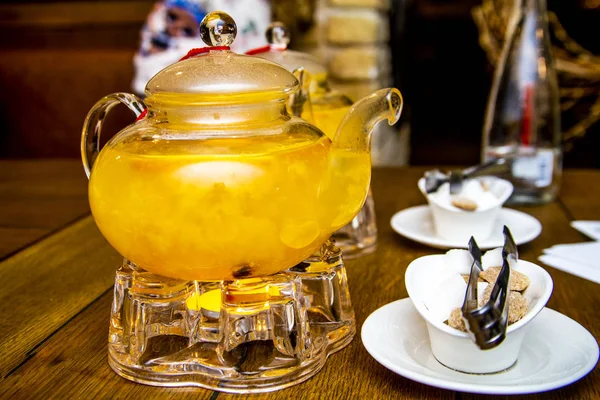 2 teaspoons of sea buckthorn and orange tea stand on tea burners, white and brown sugar on white saucers next to a wooden table in a cafe or restaurant — Stock Photo, Image