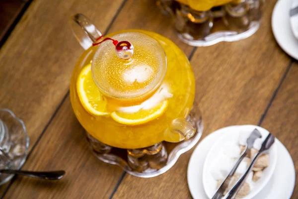 Čajová lžička z mořského pohanu a pomerančový čaj na čajových hořácích, bílý a hnědý cukr na bílých talířů vedle dřevěného stolu v kavárně nebo restauraci — Stock fotografie