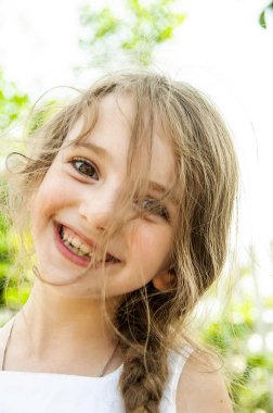 İnanıyor güneşli bir günde mutlu bir küçük kızın saçlarını geliştirir