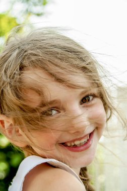 İnanıyor güneşli bir günde mutlu bir küçük kızın saçlarını geliştirir