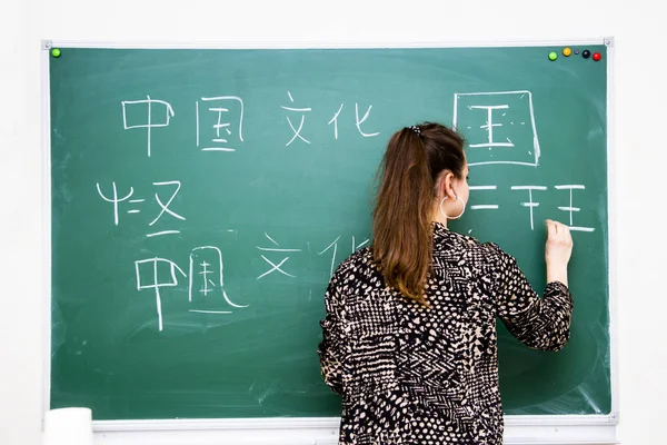 O professor perto da diretoria da escola escreve caracteres chineses — Fotografia de Stock